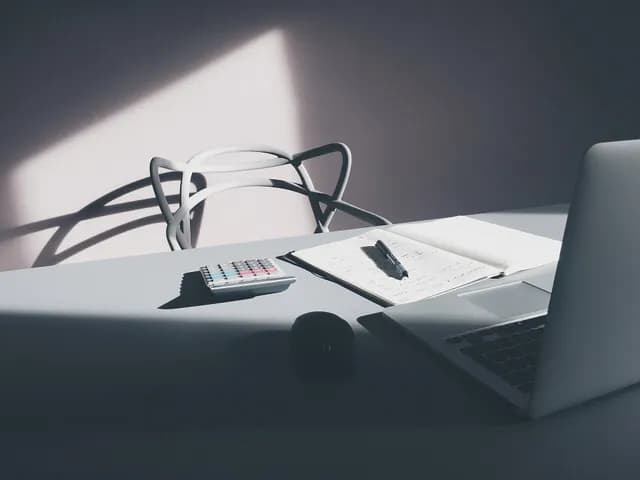 مكتب عليه حاسوب محمول وآلة حاسبة وأوراق وقلم، في إشارة إلى مراجعة قسيمة الراتب